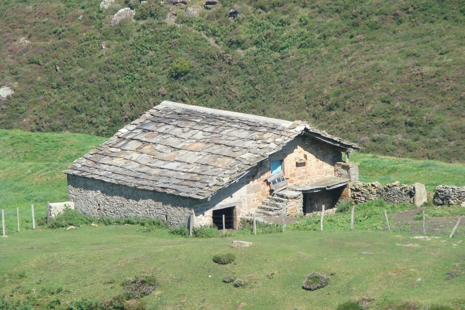 Cabaña pasiega de piedra con tejado de lastras en un prado de Cantabria