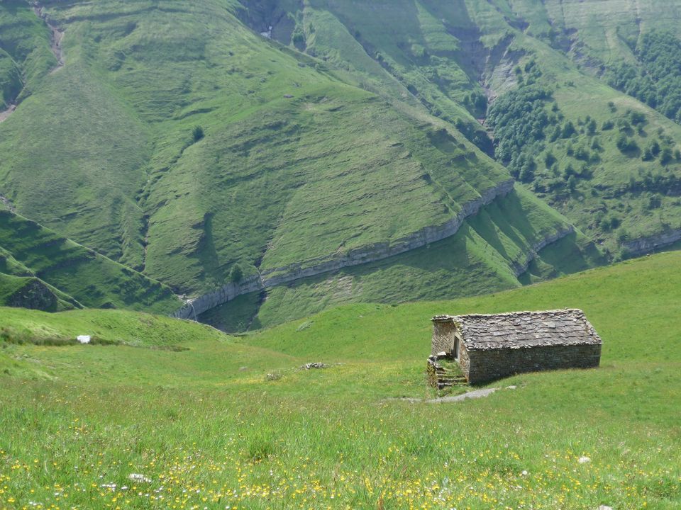 Cabaña pasiega en una ladera del valle del Pas, en Cantabria, con las montañas al fondo